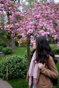 Woman standing by pink flowering tree