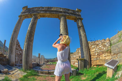 Full length of woman standing against blue sky