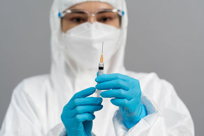 Midsection of doctor holding syringe against white background