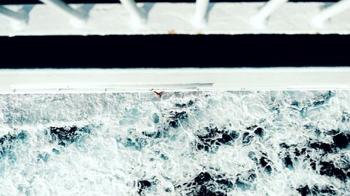 Directly above shot of sea and railing on sunny day