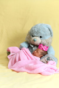 Baby girl with teddy bear and blanket on sofa