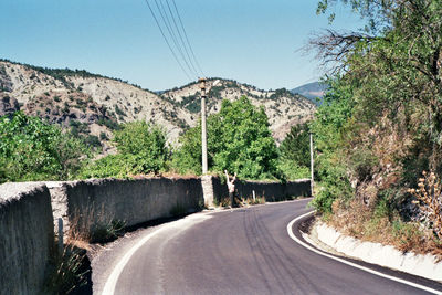 Road amidst trees and mountains against sky