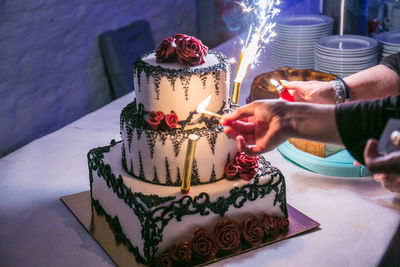 Cropped hands of women igniting candles on cake