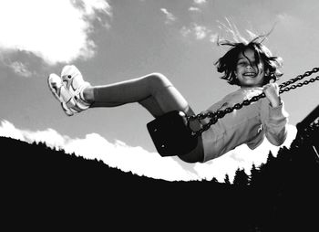 Portrait of happy girl swinging against sky