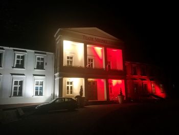 Illuminated building by street at night