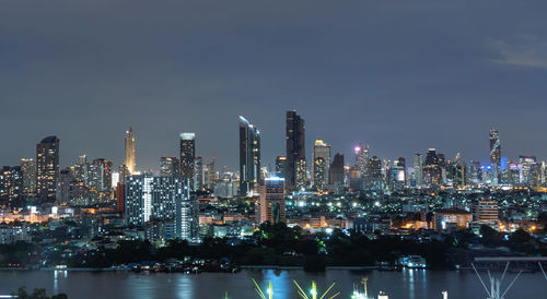 Illuminated buildings in city against sky at night