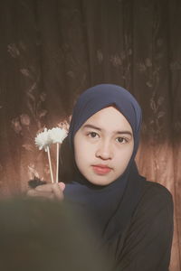 Portrait of a beautiful young woman standing against plants