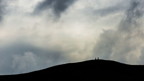 Low angle view of silhouette mountain against cloudy sky