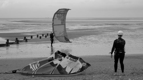 Rear view of people on beach against sky