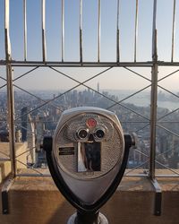 Close-up of coin-operated binoculars against cityscape