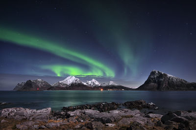 Scenic view of sea and snowcapped mountains against sky at night