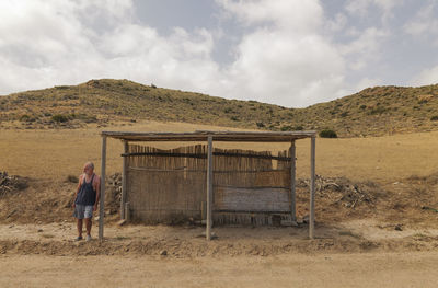 Adult man waiting bus in a wooden bus stand in nature park in summer