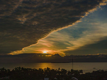 Scenic view of sea against dramatic sky during sunset