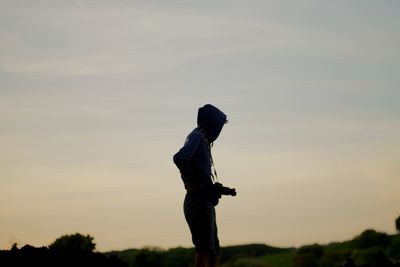 Low angle view of man standing against sky during sunset