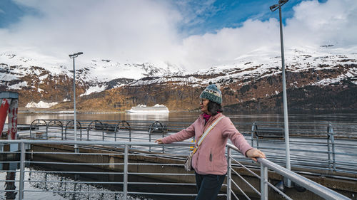 Rear view of woman standing on railing against mountain