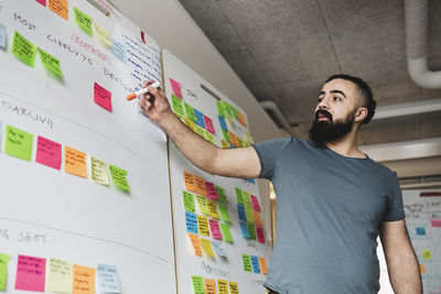 Low angle view of engineer looking at adhesive note on whiteboard