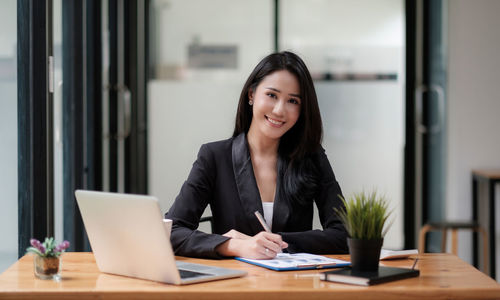 Portrait of woman using mobile phone at table