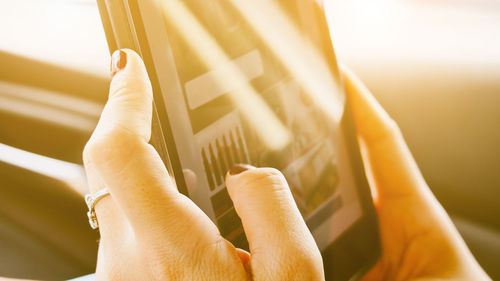 Cropped image of woman using digital tablet in car