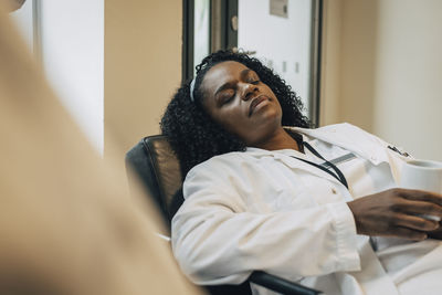 Tired female doctor taking nap during coffee break in hospital