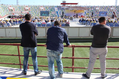 Rear view of people standing in front of playing soccer