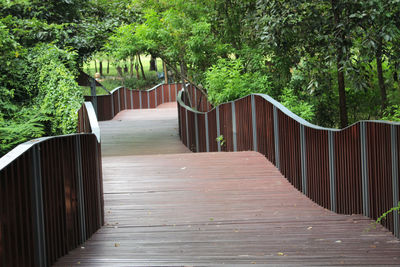 Wooden footbridge amidst trees in forest