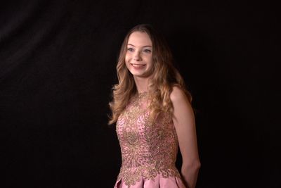 Smiling young woman looking away against black background