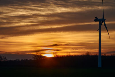 Silhouette trees on field against sky during sunset