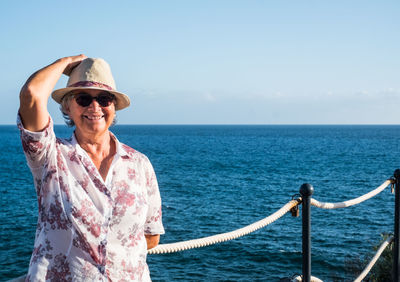 Portrait of smiling senior woman standing at sea 