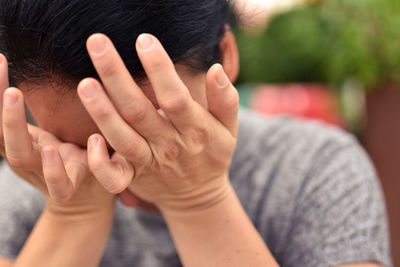Close-up of sad woman rubbing eyes while crying outdoors