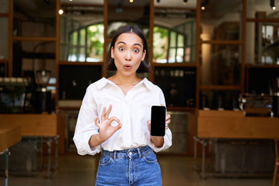 Portrait of young woman standing in cafe