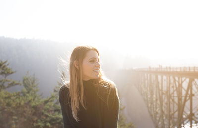 Portrait of young woman standing against sky