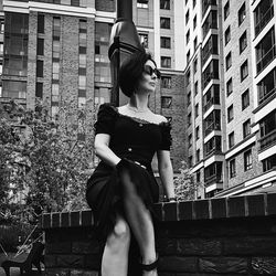 A pretty charming middle-aged woman in a black dress and sunglasses strolls through the city street