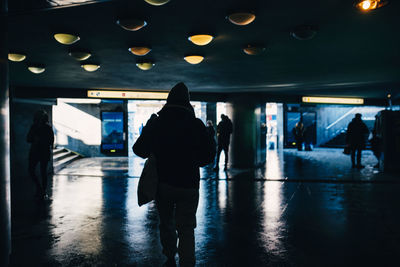 Rear view of silhouette people walking in illuminated corridor