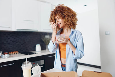 Portrait of young woman using mobile phone while sitting at home