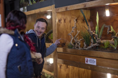 Young man with down syndrome and young woman visiting reptile exhibition