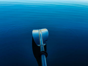 Close-up of oar above blue sea
