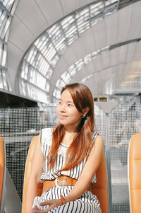 Woman looking away while sitting at airport departure area