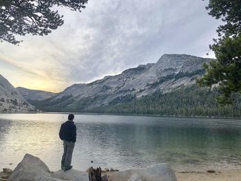Rear view of man standing by lake against mountains