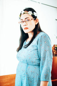 Portrait of young woman standing against wall