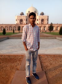 Full length portrait of man standing against historical building