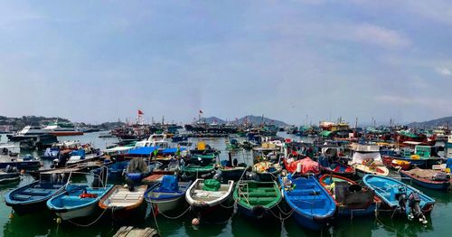 Boats moored at harbor against sky