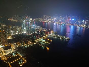 High angle view of illuminated city by sea against sky