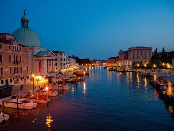 Boats in canal amidst buildings in city at night