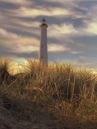 Lighthouse on field against sky