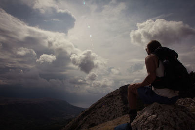 Rear view of couple on rock against sky