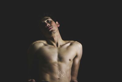 Young man standing against black background