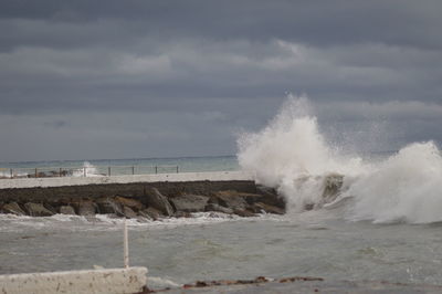 Waves splashing on shore against sky