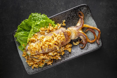 Pla muek tod kra tiam, thai food, fried squid with garlic served with lettuce, top view