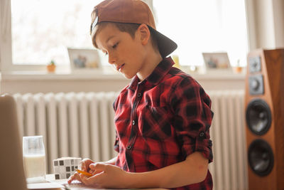Cute boy with a cap studying at home due to coronavirus epidemic.