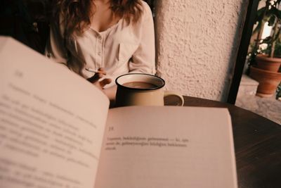 Midsection of woman with coffee cup on table